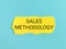 Sales methodology written on yellow paper strip isolated on bluish background.