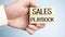 sales playbook on wooden block with in businessman hands