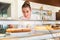 Sales woman in bakery shop putting cakes on display