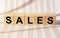 Sales word built with letter cubes on newspaper background