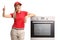 Salesgirl leaning on an electrical oven and giving thumb up