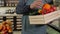 A salesman in an apron putting fruit in a wooden box in a grocery store.