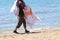 salesman with cloths and fabrics walks on the sunny beach in sum