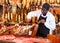 Salesman cutting delicious ham in butcher shop