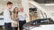 A salesman demonstrates a car with an open hood to an elderly Caucasian couple in a car dealership.