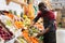 Salesman filling counter with vegetables and fruits