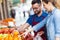 Salesman helping customer to choose some types of fruits in heal in fruitshop.