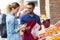 Salesman helping customer to choose some types of fruits in health grocery shop.