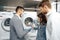 Salesman in hypermarket wearing medical mask demonstrates his clients a new washing machine