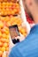 Salesman making a photo with her smartphone to the oranges in fruitshop.