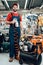 Salesman is posing with compressor paint sprayer on foreground in power tools store.