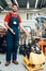 Salesman is posing with plate compactor on foreground in power tools store.