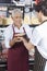 Salesman Receiving Cheese From Colleague In Grocery Shop