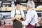 Salesman Receiving Cheese From Colleague In Shop