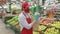 Salesman in red face mask standing in grocery store selecting fresh apples. Courier working in supermarket delivery
