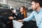 Salesman shows the car to a young client of a car dealership