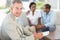 Salesman smiling at camera with couple on sofa behind him