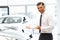 Salesman Standing at the Car Showroom and Showing New Cars