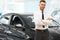 Salesman Stands Near Brand New Car. Car Showroom