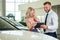 Salesman in suit showing catalog to female blonde customer in dealership salon