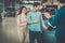 Salesman talking to a young couple at the dealership showroom.