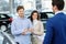 Salesman talking to a young couple at the dealership showroom.