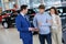 Salesman talking to a young couple at the dealership showroom.