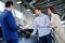 Salesman talking to a young couple at the dealership showroom.