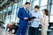 Salesman talking to a young couple at the dealership showroom