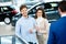 Salesman talking to a young couple at the dealership showroom