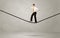 Salesman walking on rope in grey space