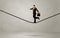 Salesman walking on rope in grey space