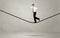 Salesman walking on rope in grey space