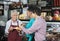 Salesperson Offering Samples To Customers In Cheese Shop