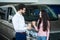 Salesperson showing vehicle to potential customer in dealership and drink coffee