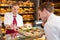 Saleswoman in bakery presenting sandwiches to customer