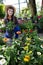 A saleswoman holds a pot of flowering asters in her hand. Garden Shop.