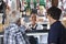 Saleswoman Selling Cheese To Male Customers At Shop