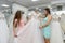 Saleswoman in wedding salon helping to young bride