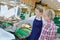 saleswoman weighting vegetables on scale in grocer