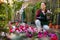 Saleswoman working in garden shop, examining and preparing for sale potted plants