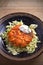 Salmon burger and cabbage salad in bowl on wooden table. Salmon fish cake and vegetables.