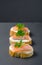 Salmon canape sandwiches with baguette on black grunge background.