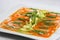 Salmon carpaccio, thin slices of salmon seasoned with olive oil and avocado