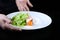 Salmon in creamy caviar sauce on a white plate. The cook serves the prepared dish. Lettuce leaves. Photo on a black background.