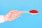 Salmon fish caviar, seafood on wooden spoon in hand, isolated on blue background