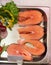 Salmon fish fillet in metal tray on ice at grocery