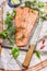 Salmon fish fillets on cutting board with knife and fresh seasoning and spices on plaid kitchen table-napkin.