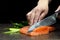 Salmon is in the hands of the Japanese chef and meticulously done, He is using a knife to slice salmon fillet for sashimi and sush