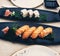 Salmon nigiri sushi, next to maki rolls on leaves in black plates - Japanese cuisine with soy sauce and wasabi - raw fish